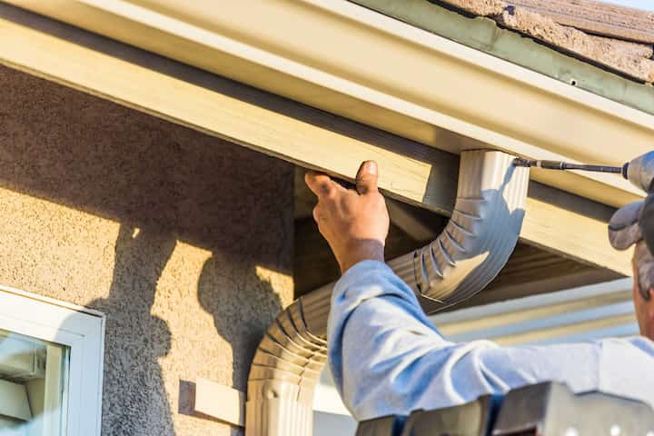 A team of workers installing seamless gutters on a commercial building in West Palm Beach